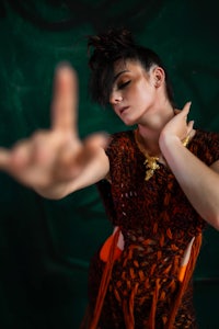 a woman in an orange dress making a hand gesture