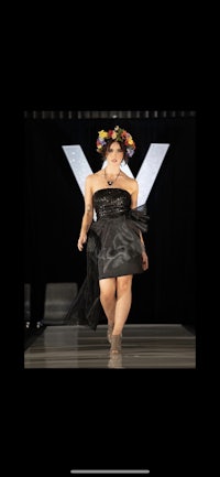 a woman in a black dress walking down the runway