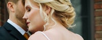 a bride and groom hugging in front of a brick building