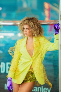 a woman wearing a yellow suit and purple gloves