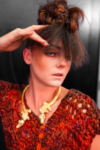 a woman is posing with her hair in a bun