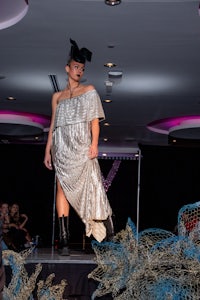 a woman in a silver dress walking down a runway